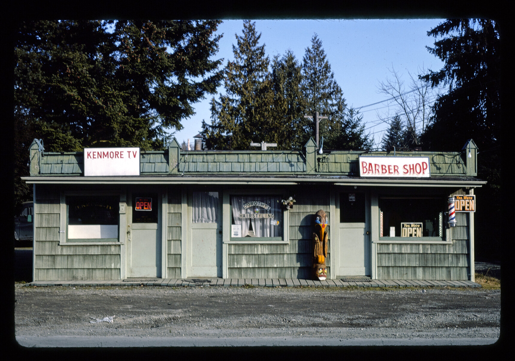 1977 photograph of the small wooden three-storefront building on the north side of Bothell Way between 68th and 73rd Avenues NE.